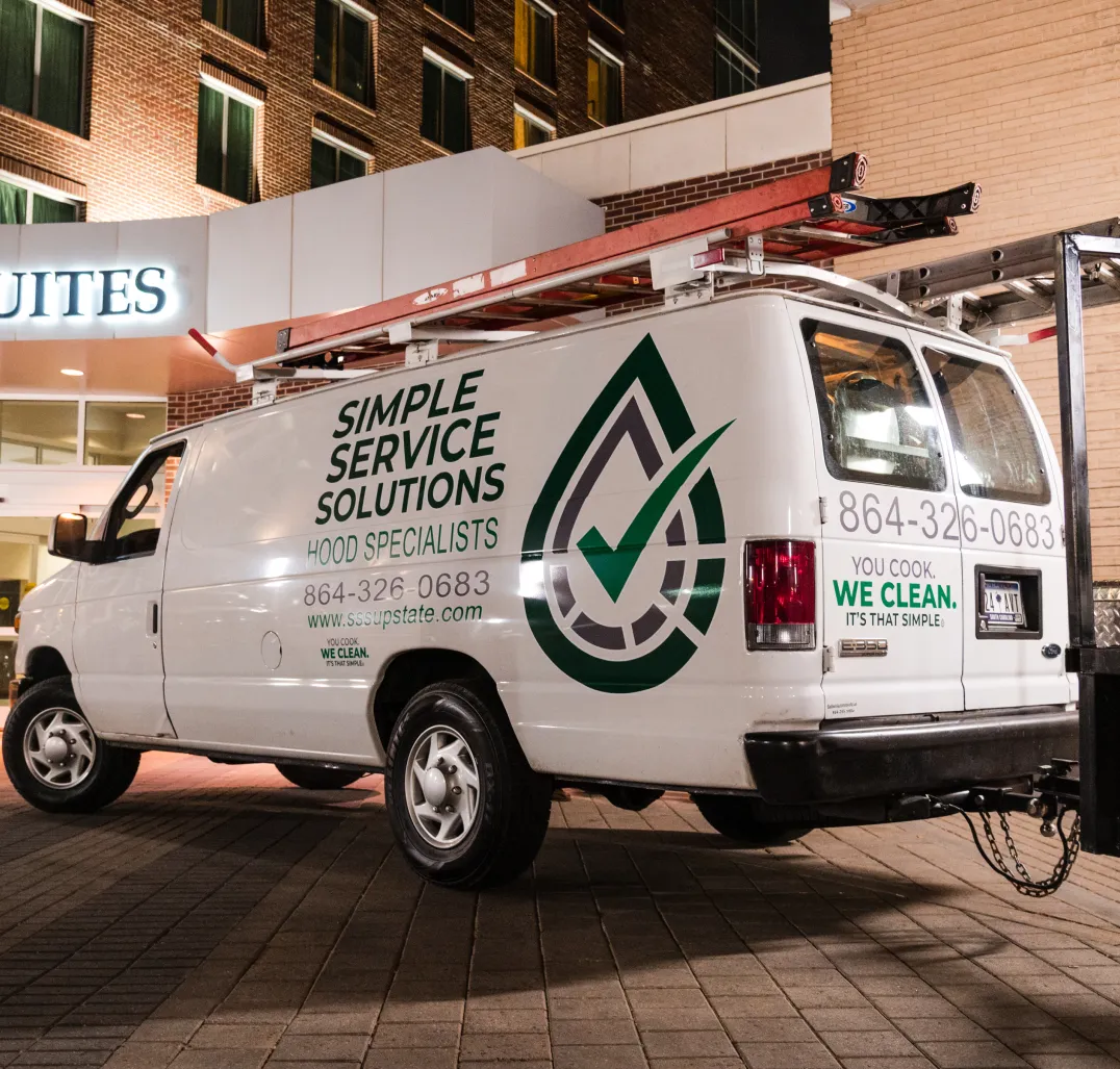 emergency-img-1 A white service van with "Simple Service Solutions" and contact info is parked outside a building at night.