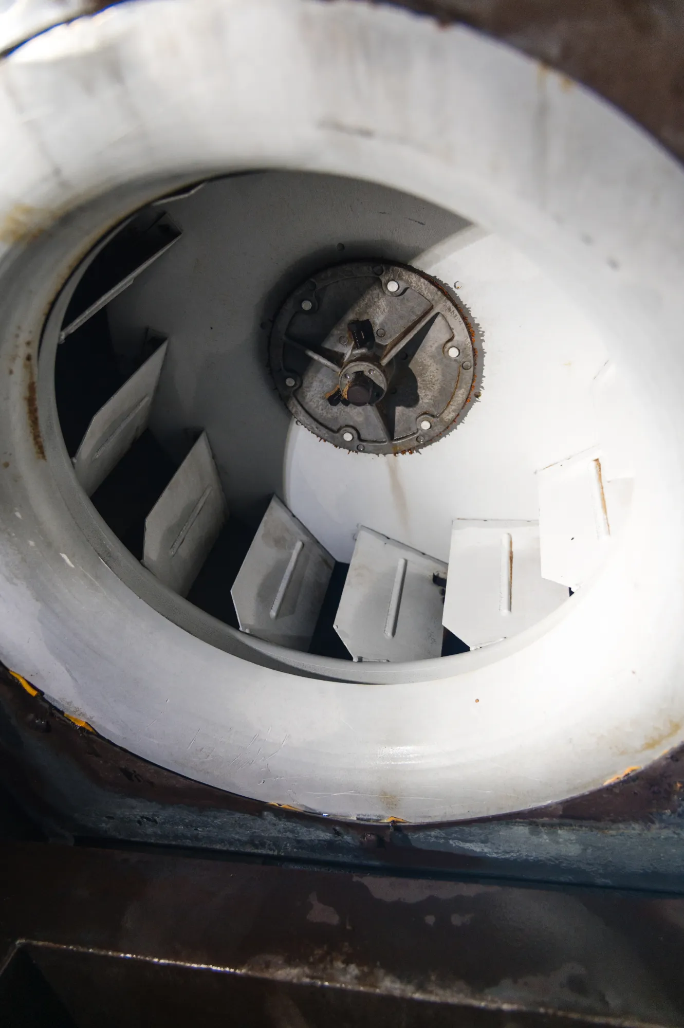 fan-2 Close-up of the inside of a metal industrial fan or turbine with white blades and a central hub.