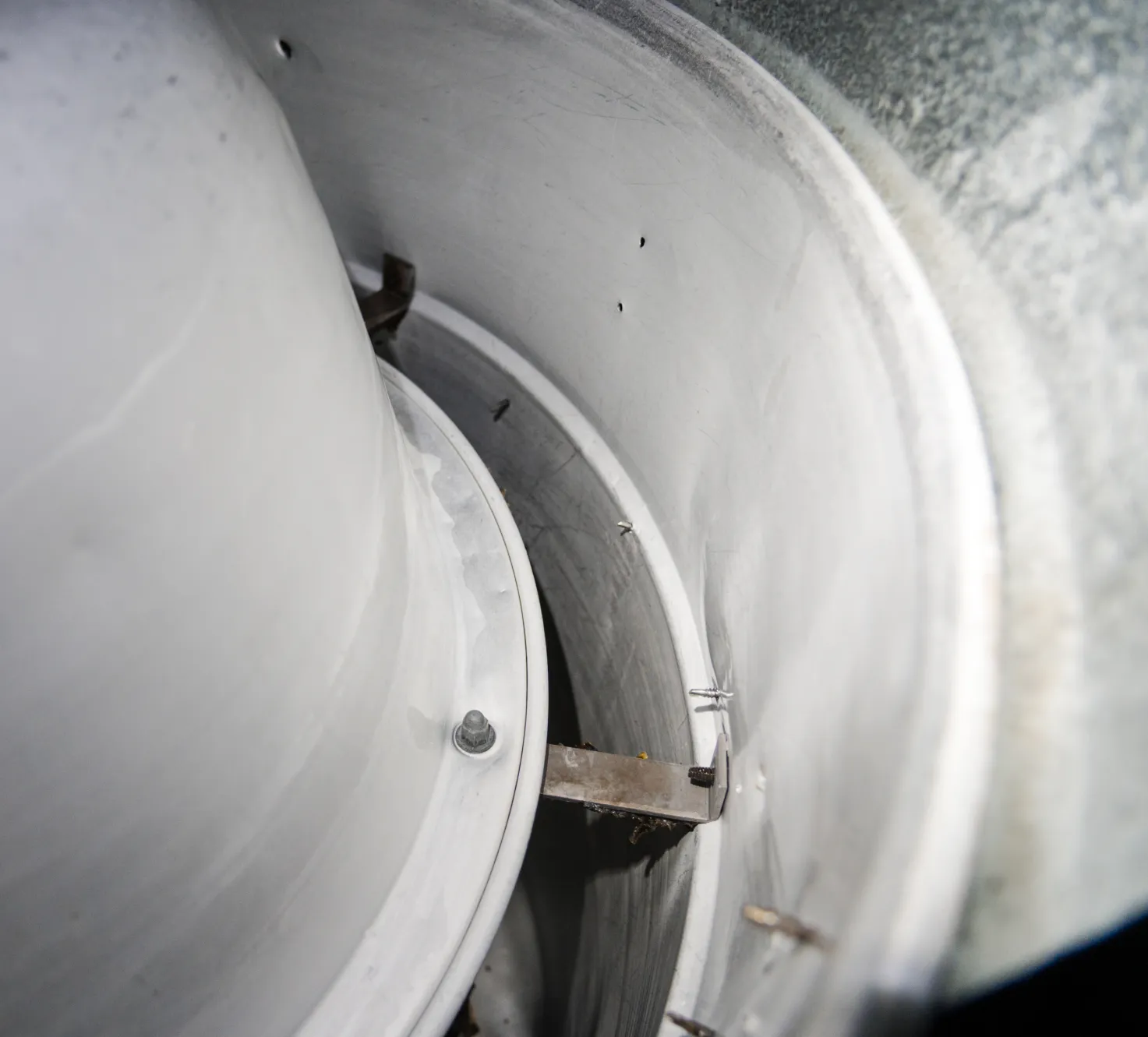 fan-3 Close-up of the inside of a metal vent or duct with some dust, bolts, and metal brackets visible.